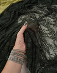 Hunter green floral stretch lace fabric held up showing intricate floral pattern