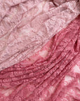 Layered pink and coral lace fabric showing color range from light pink to deep rose