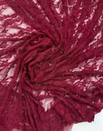 Close up deep burgundy lace fabric gathered drape showing intricate floral details