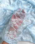 Baby Blue Floral Stretch Lace Fabric held in hand showing transparency and intricate design