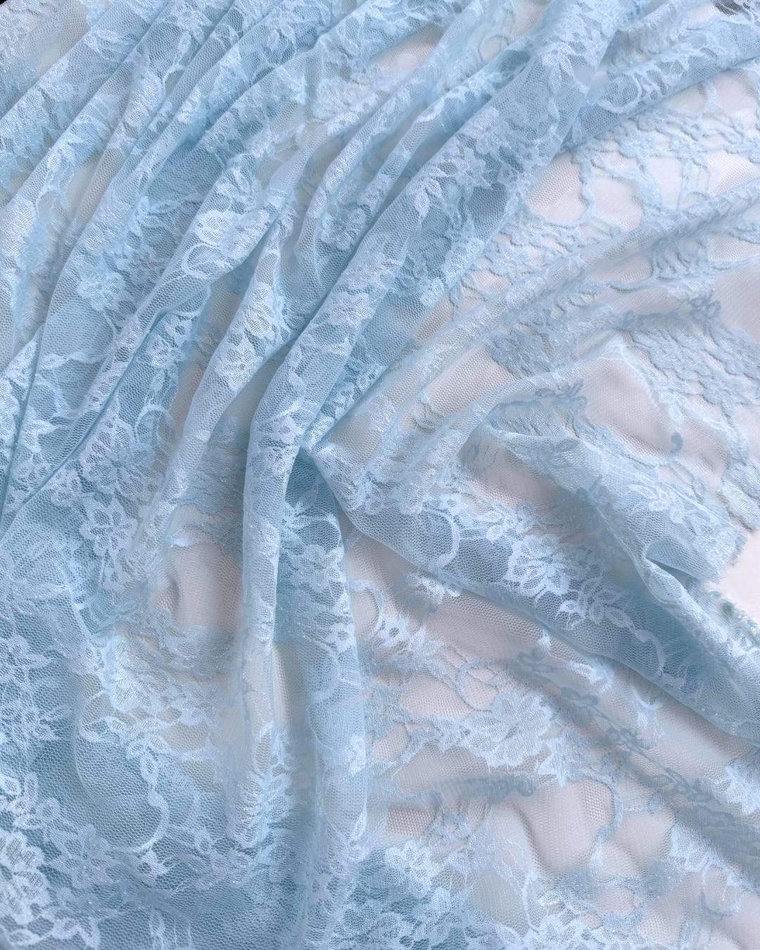 Baby Blue Floral Stretch Lace Fabric draped in soft pastel blue folds