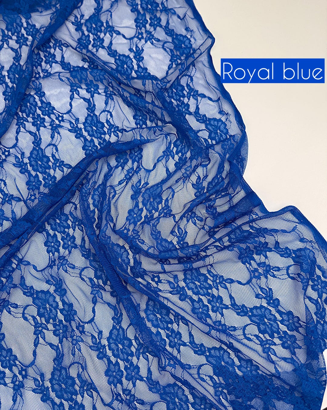 Royal blue floral stretch lace fabric draped with royal blue label, 4-way stretch