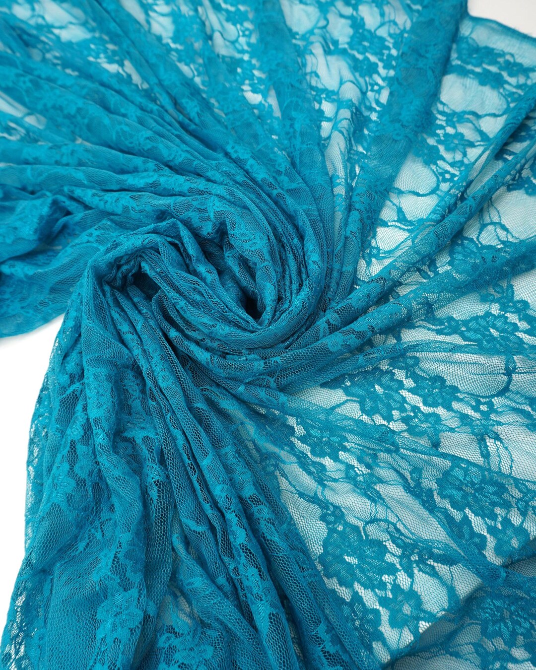 Turquoise teal floral stretch lace fabric draped and swirled showing vibrant color