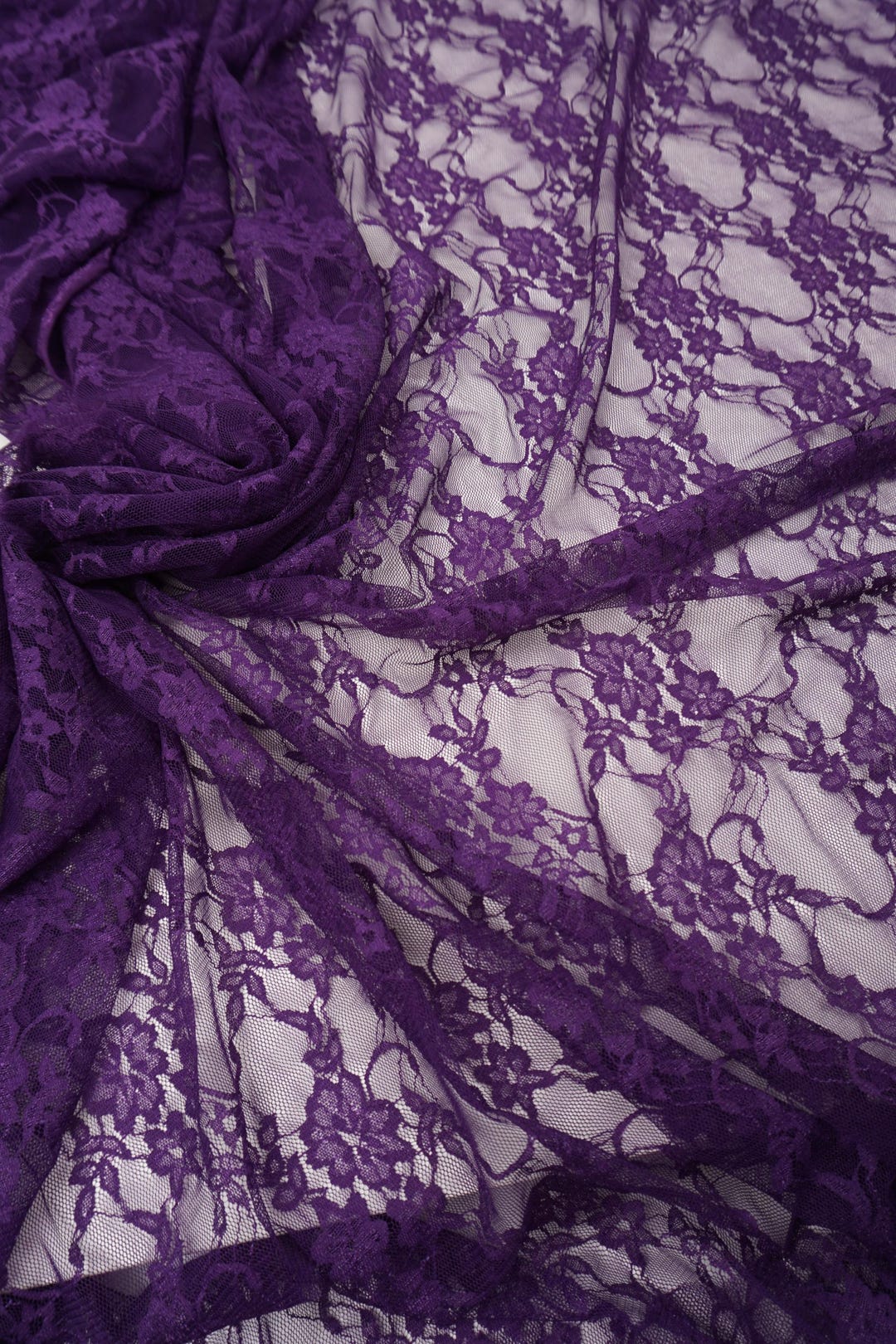 Deep eggplant purple floral stretch lace fabric close-up showing delicate floral pattern