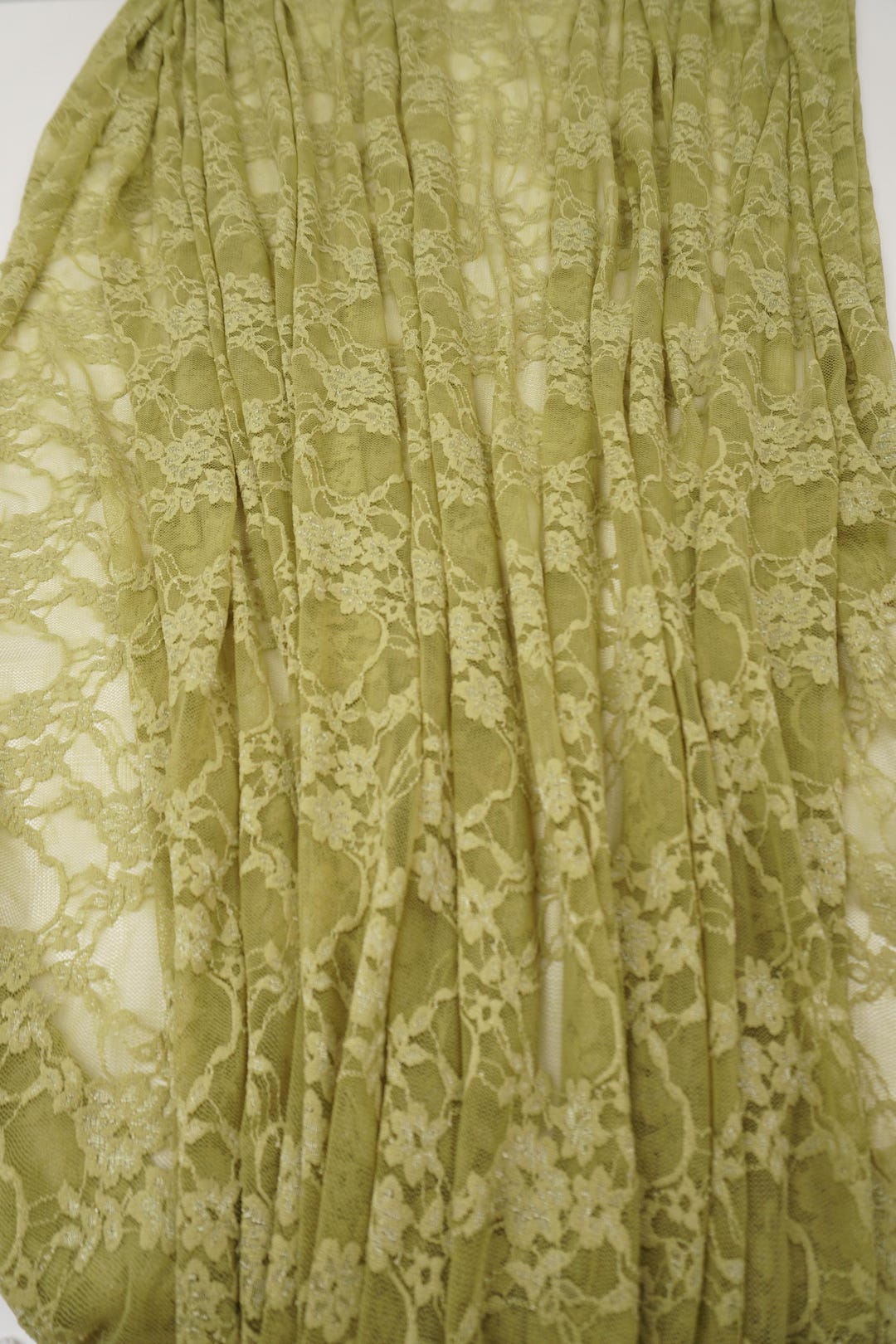 Close-up detail of moss green floral stretch lace fabric showing intricate pattern