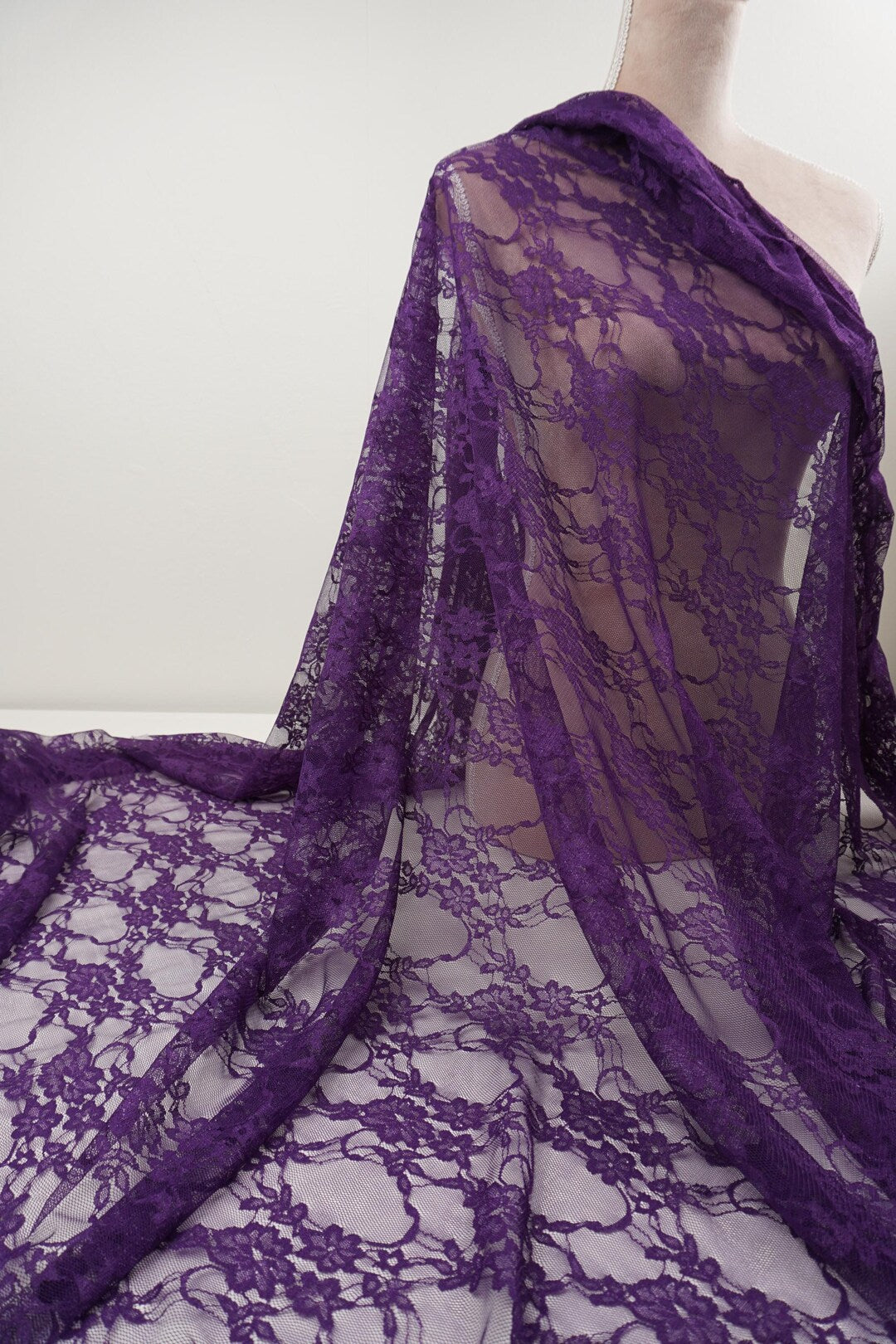 Deep eggplant purple floral stretch lace fabric draped on mannequin showing drape