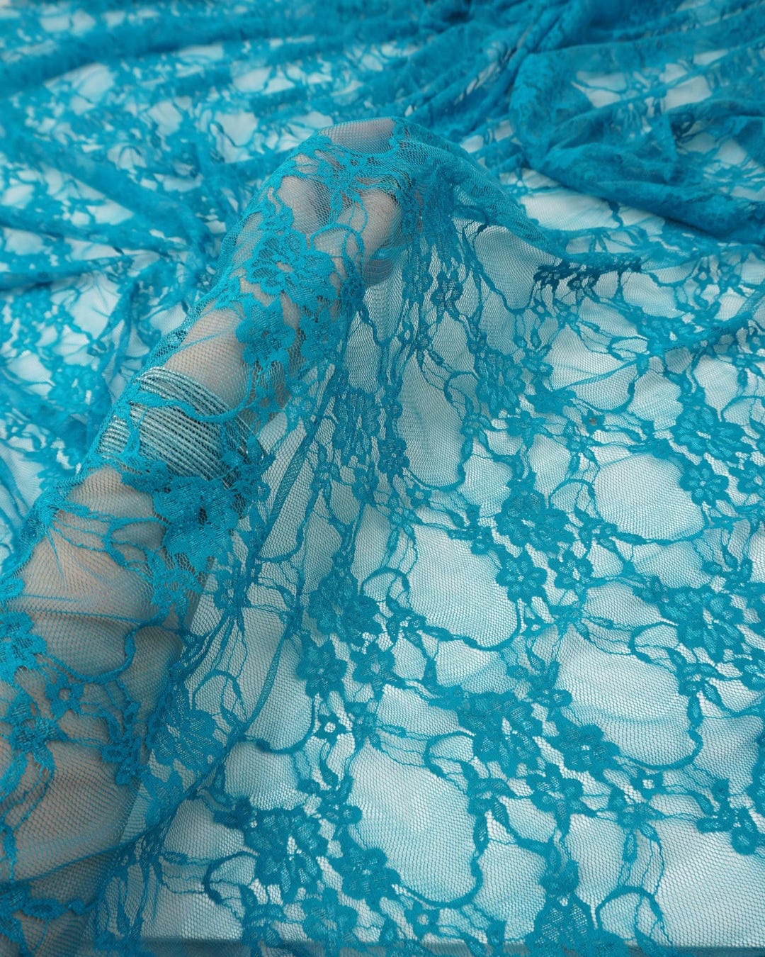 Turquoise floral stretch lace fabric semi-transparent showing intricate floral details