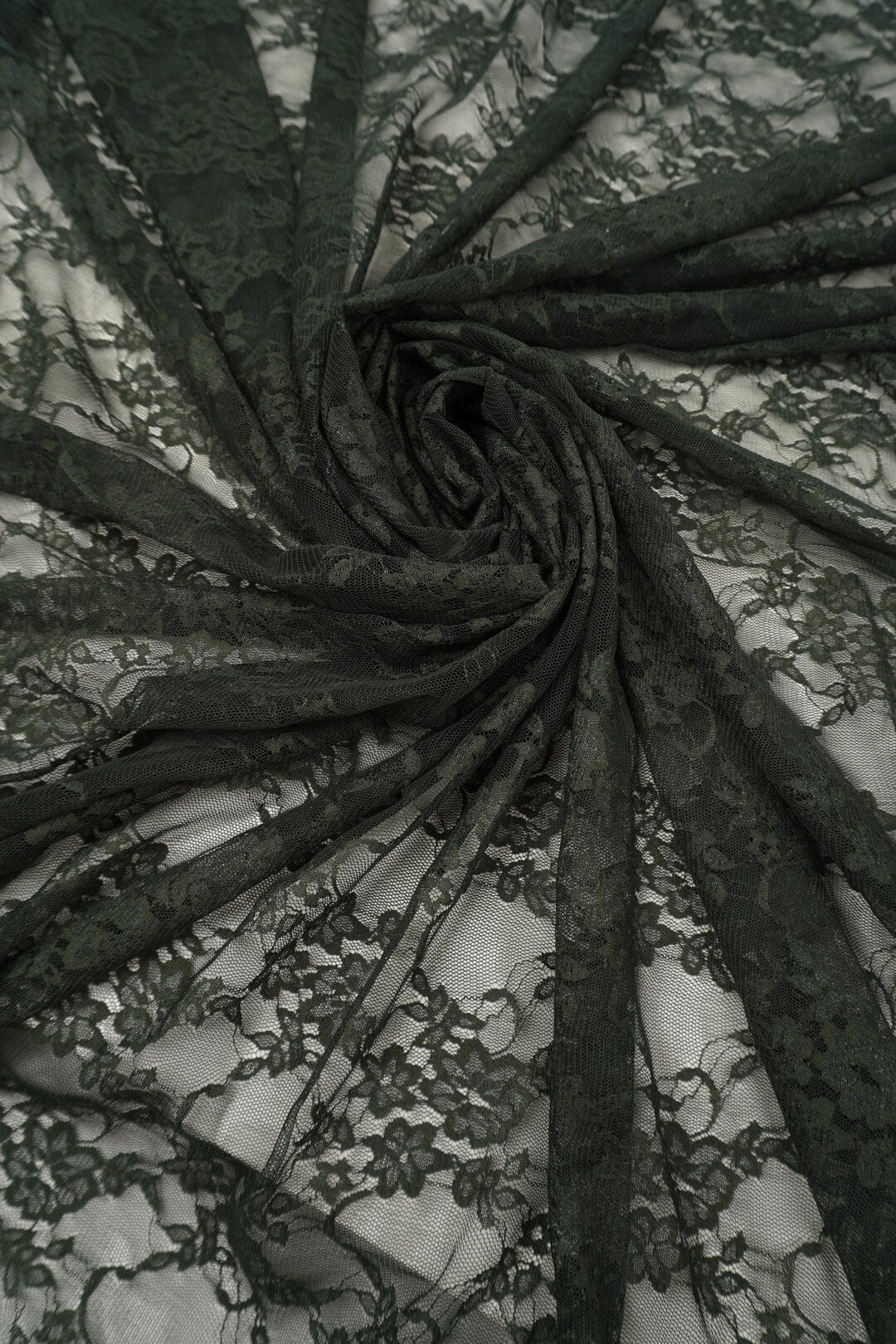 Hunter green floral stretch lace fabric draped and folded showing deep forest green color