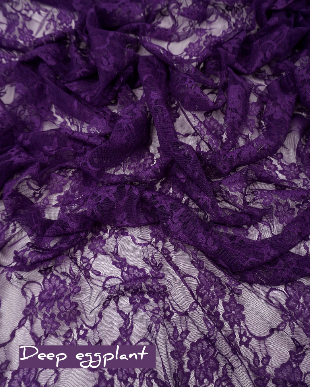 Deep eggplant purple floral stretch lace fabric draped with deep eggplant label