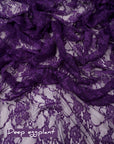 Deep eggplant purple floral stretch lace fabric draped with deep eggplant label