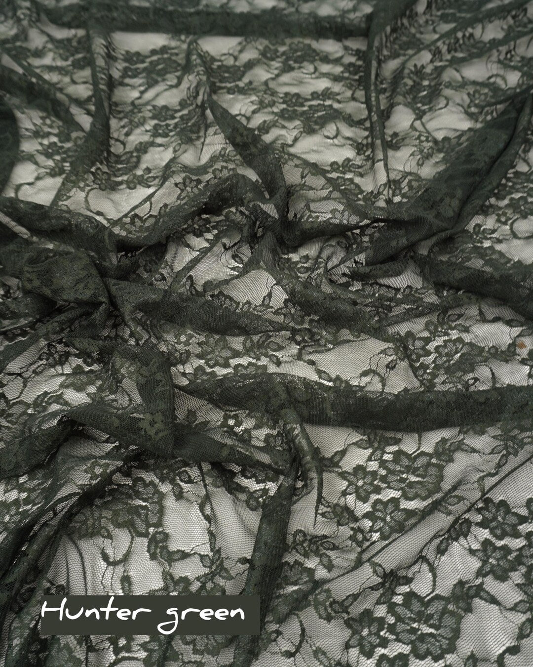 Hunter green floral stretch lace fabric draped with hunter green label