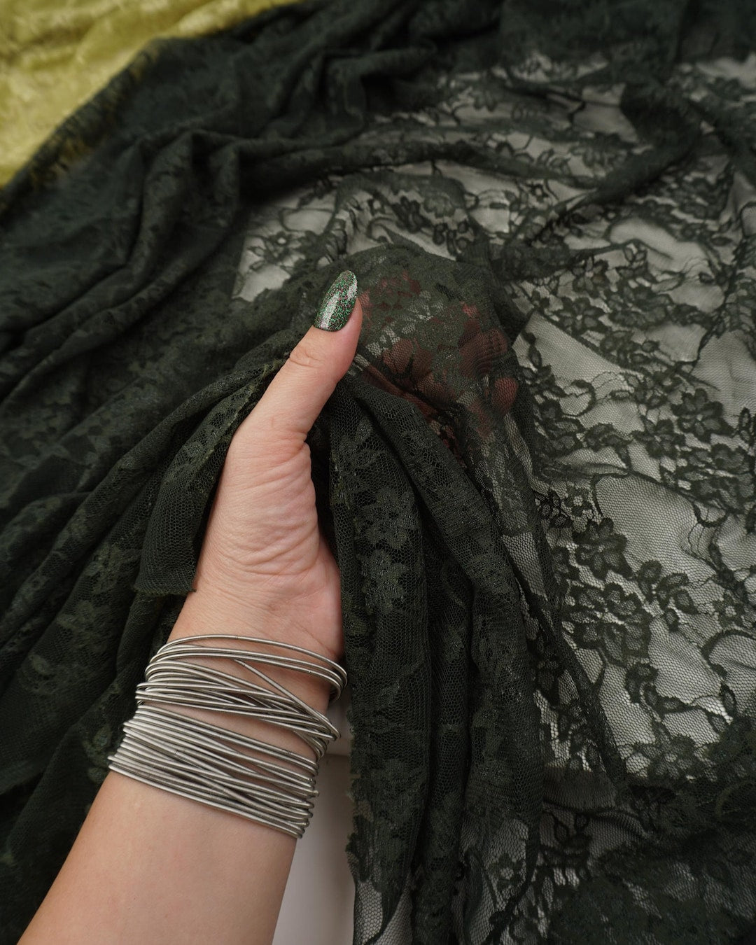 Hunter green floral stretch lace fabric held up showing intricate floral pattern