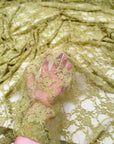 Moss green floral stretch lace fabric close-up held up showing sheer floral pattern