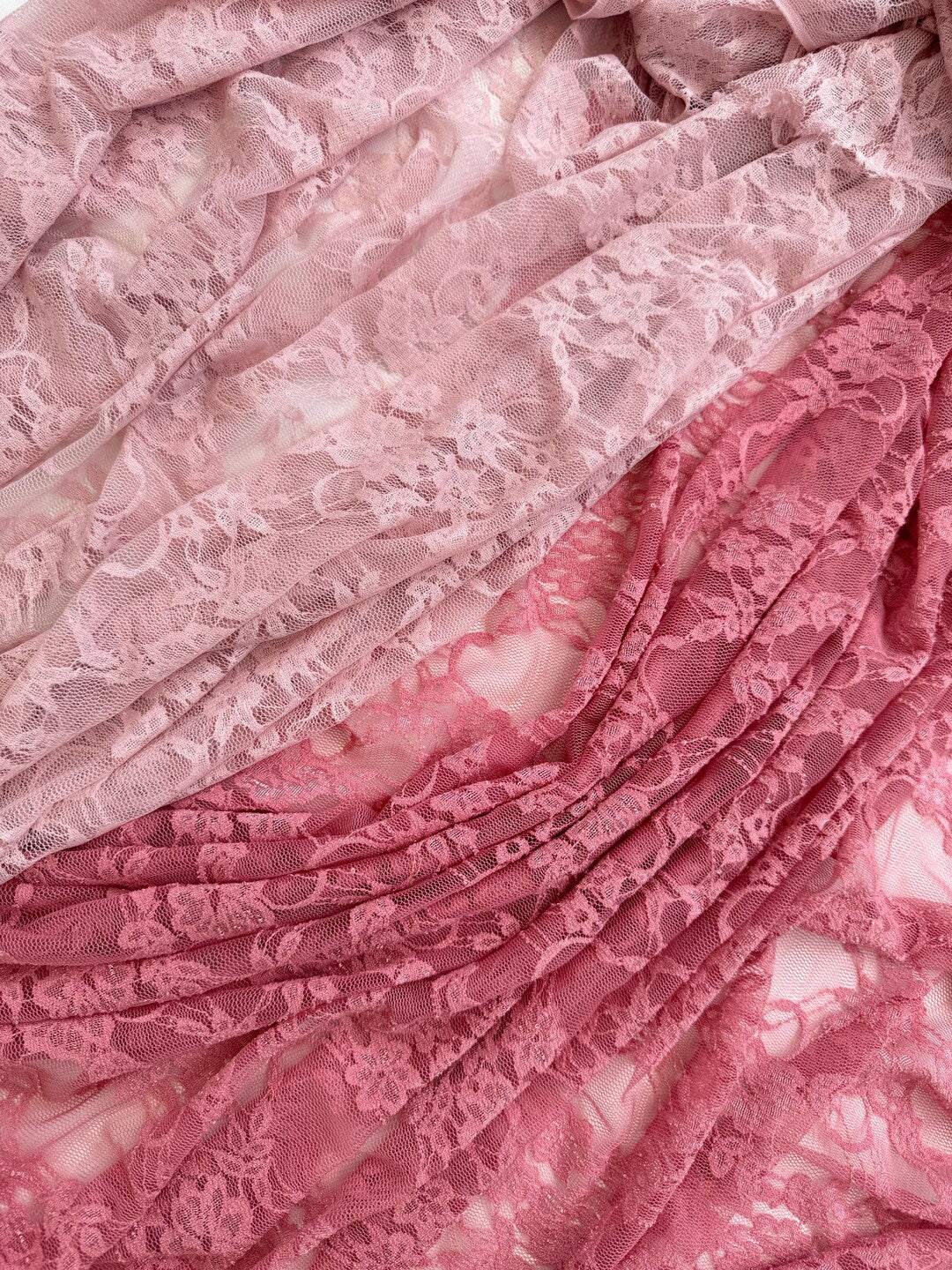 Layered pink and coral lace fabric showing color range from light pink to deep rose