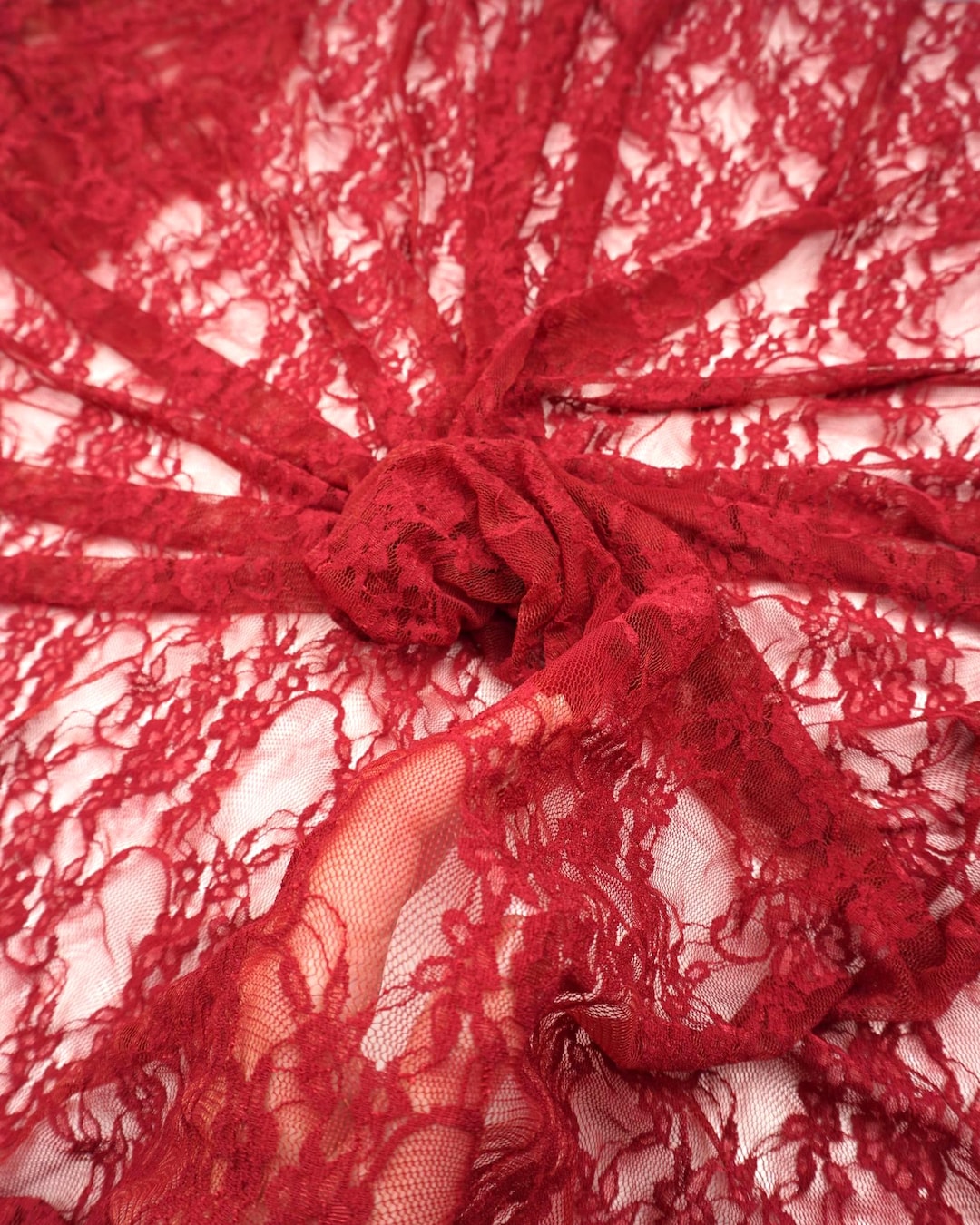 Red Floral Stretch Lace Fabric close up deep red bunched and draped semi-transparent