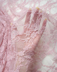 Blush dusty pink vintage floral stretch lace fabric held up showing delicate sheer pattern