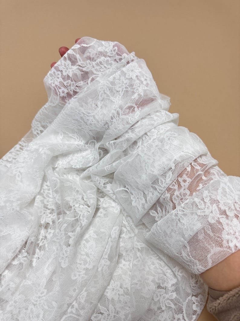 Ivory Floral Stretch Lace Fabric gathered and held showing lightweight texture