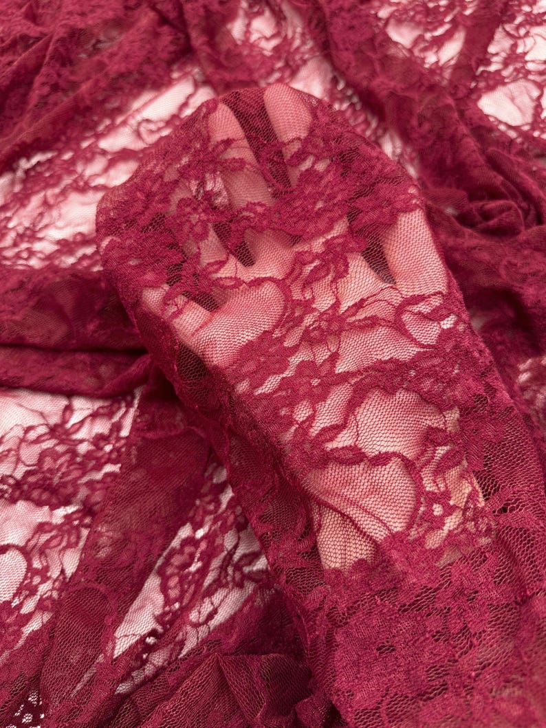Close up burgundy lace fabric intricate floral pattern sheer draped