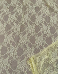 Close up pale yellow lace fabric with intricate floral interconnected design