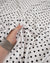 Ivory satin fabric with small black polka dots draped in soft folds