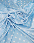 Dusty blue satin fabric with small white polka dots draped in soft folds