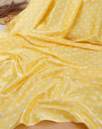 Banana yellow and white polka dot stretch satin fabric draped in soft folds