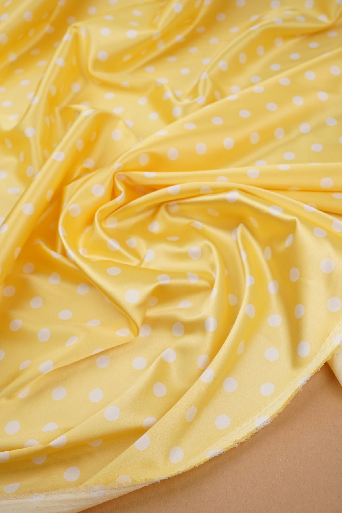 Yellow polka dot satin fabric showing sheen
